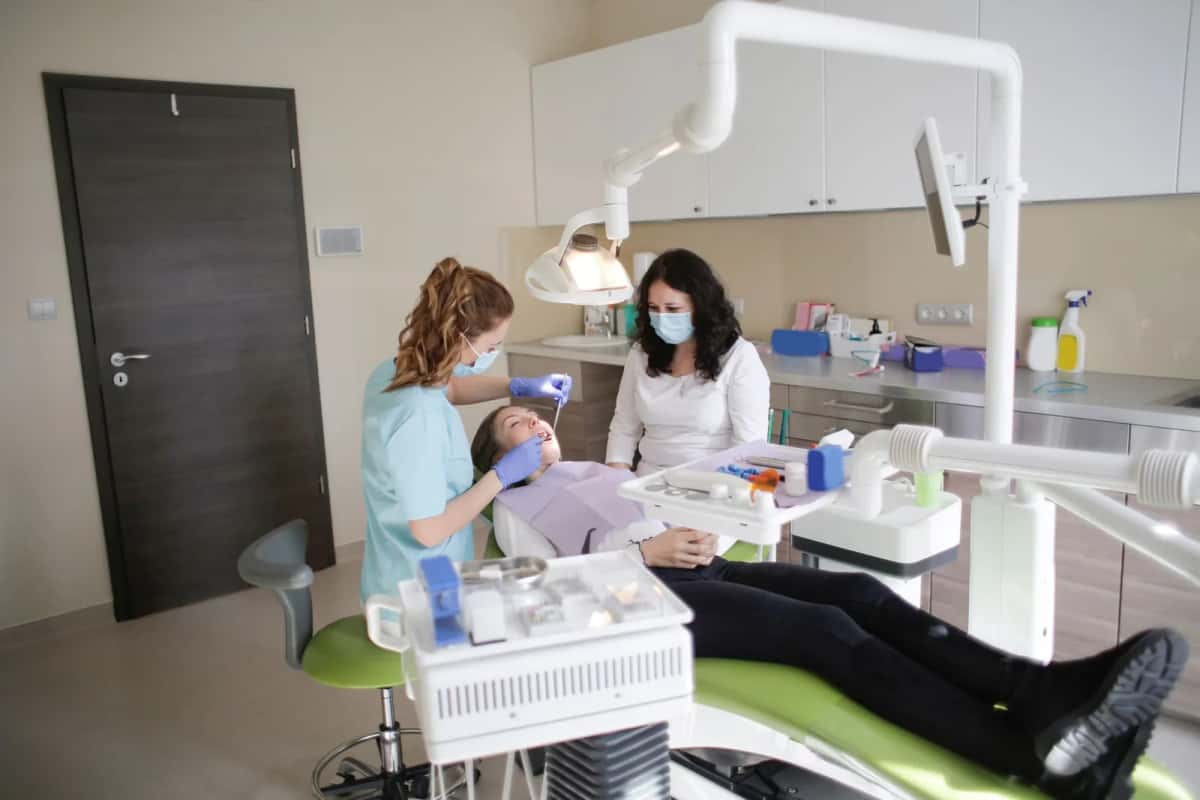 Dentiste et assistante soignant une patiente en cabinet
