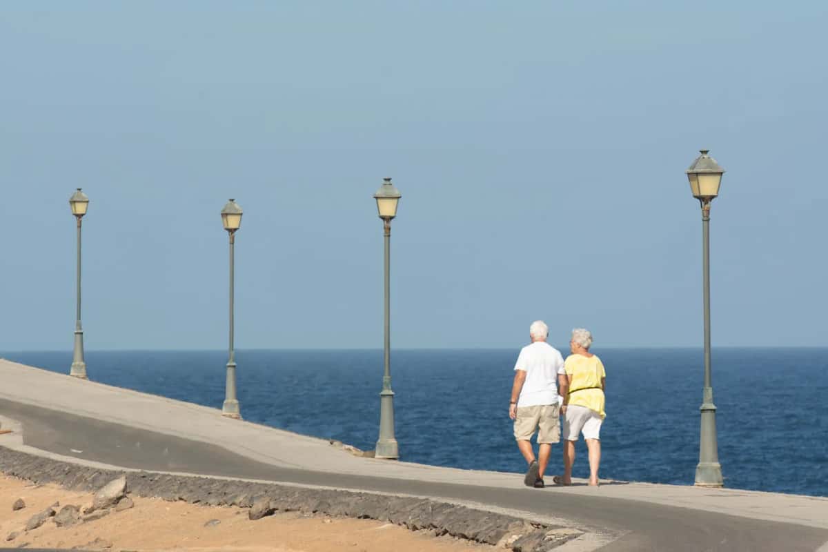 Couple de retraités marchant sur une promenade en bord de mer