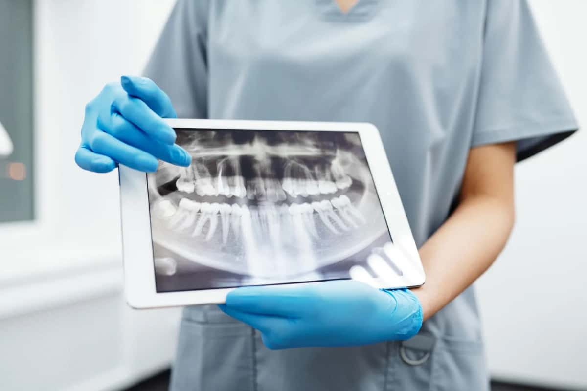 Praticienne examinant une radiographie panoramique dentaire sur tablette