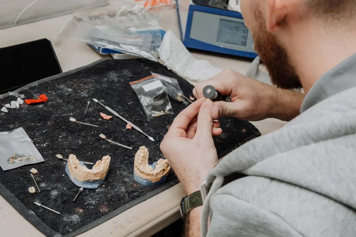 Technicien dentaire façonnant une prothèse sur un modèle en plâtre